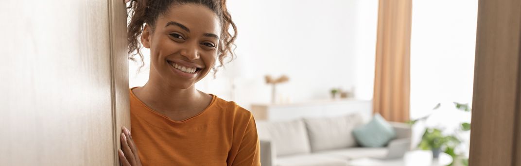 A Millennial opens the door to her home.