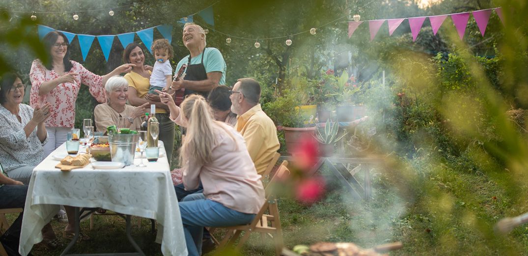 A family gathers for an outdoor meal accompanied by guitar music.