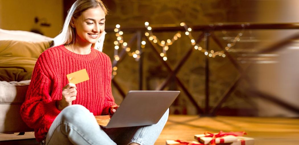 A woman uses her bank card for holiday shopping on her laptop.