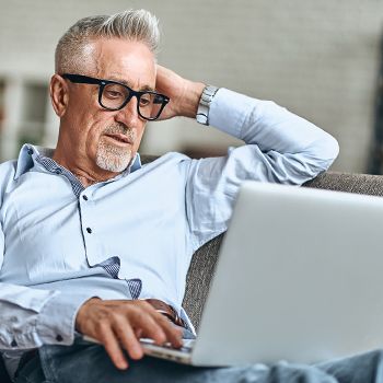 A gray-haired man shops for a new car using the AutoSmart website.