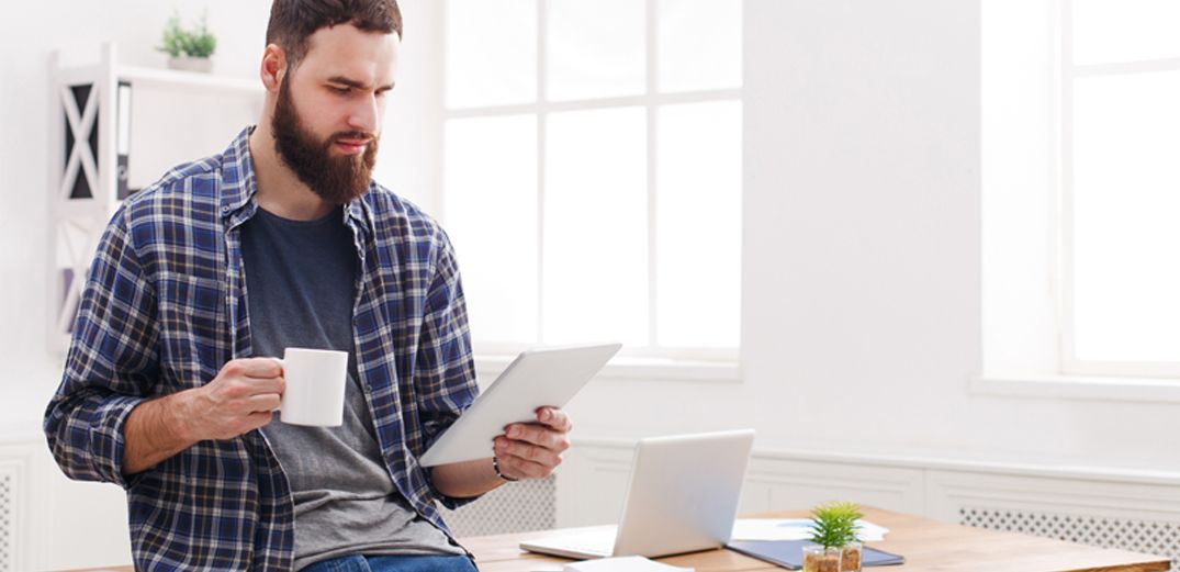 A bearded man uses a tablet to log into a Zoom call with a Patelco Insurance advisor.