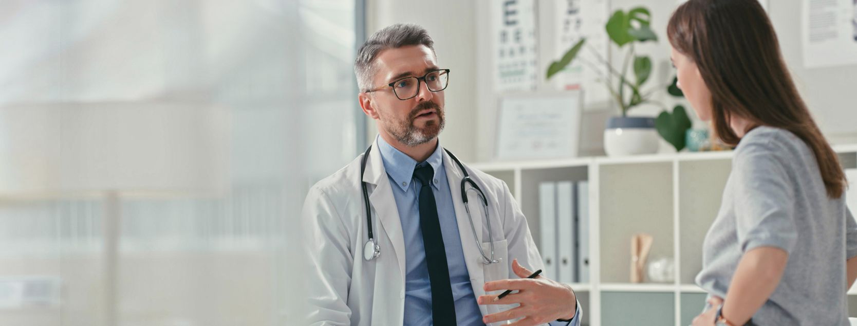 A doctor speaks to his female patient at an appointment.