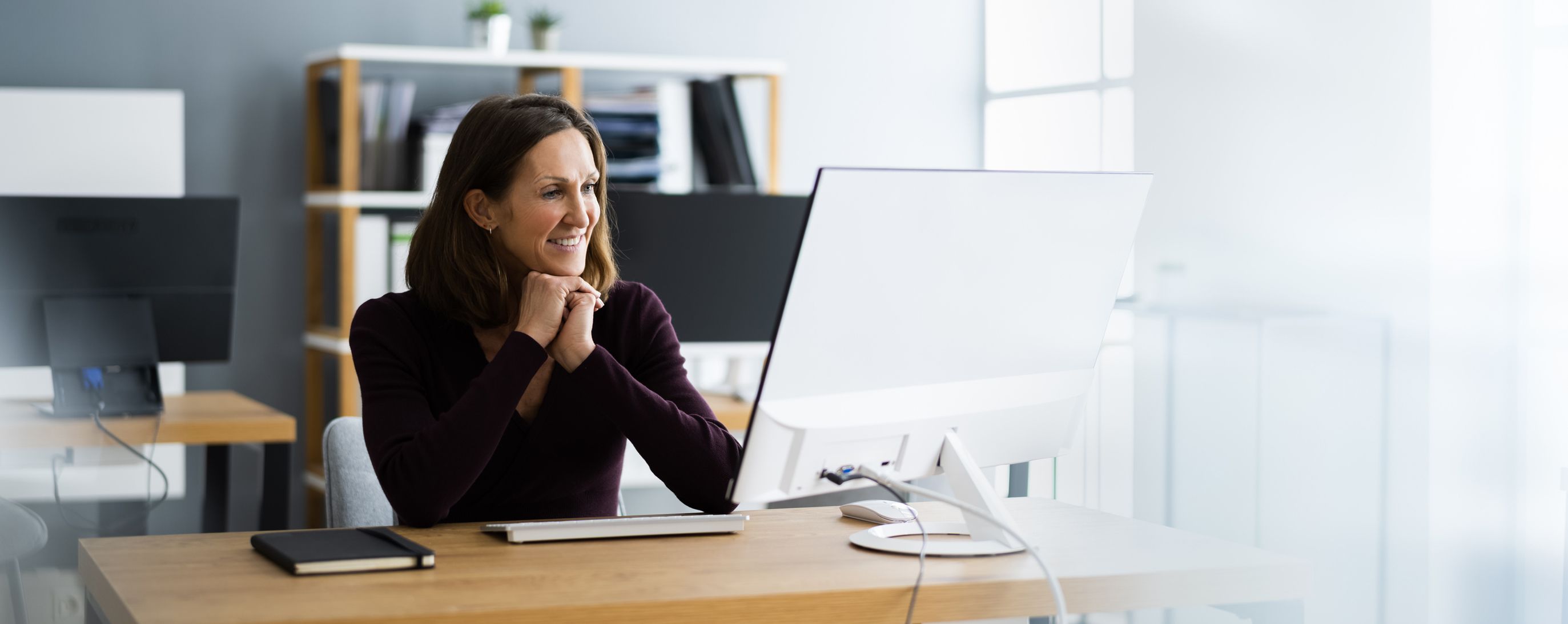 A middle-aged woman watches a Patelco webinar from her computer.